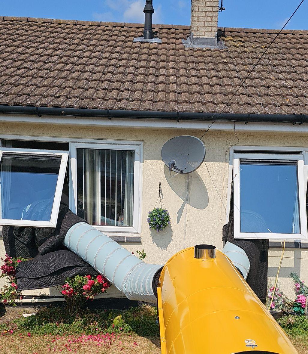 Bed bug heat treatment in progress at a bungalow with ducting routed through windows