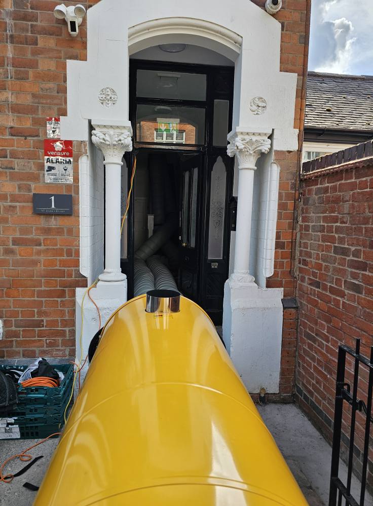 Professional heat treatment heater with ducting entering a brick property through the front doorway